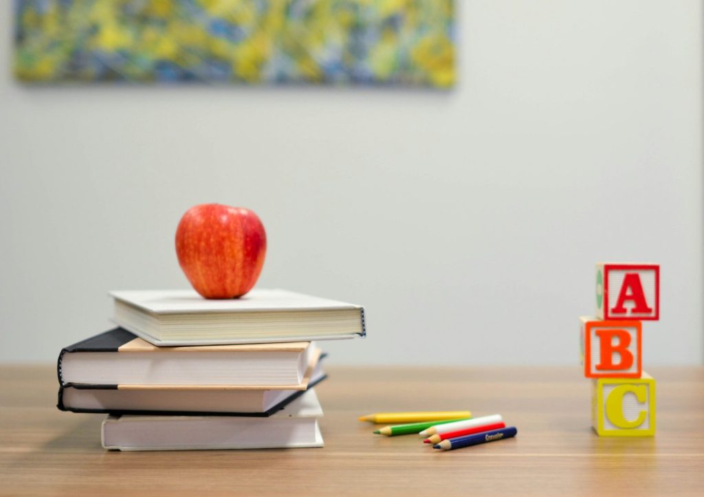 Apple on books with colorful pencils